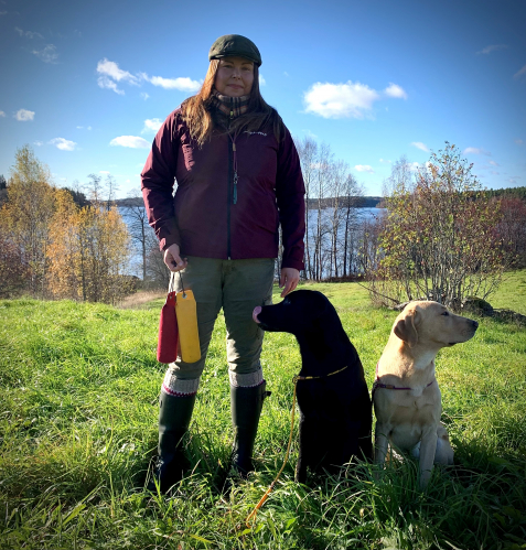 Jenna Laakso 2 koiran kanssa järvimaisemassa.